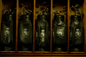 Classic black leather golf bags bearing the Villa d’Este crest, neatly lined up in wooden cubbies.