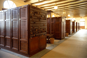 Elegant vintage-style wooden locker room with rows of lockers and a key wall, warmly lit by hanging lamps.