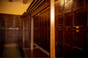 Traditional wooden locker room with dark wood lockers and bench seating, showcasing timeless golf club charm.