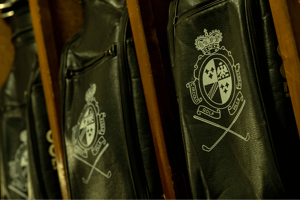Close-up of black leather golf bags with the Golf Club Villa d’Este crest, stored in wooden compartments.