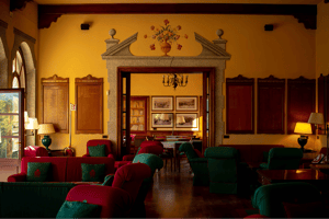 Warmly lit lounge at Golf Club Villa d’Este, featuring classic wooden furnishings, red and green armchairs, and historic honor boards.