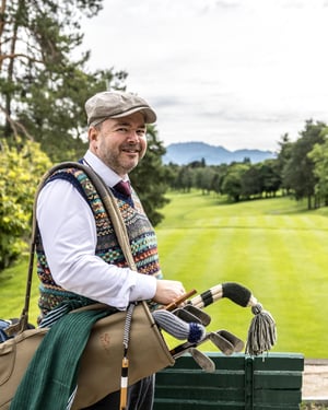 Hickory golfer carrying a traditional golf bag filled with vintage clubs overlooking the fairway at Villa d’Este.