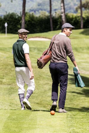 two participants walking across the course carrying traditional golf equipment during the Hickory Masters.