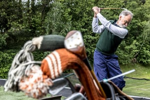 Ritratto di un partecipante all’Hickory Masters in piedi sul fairway con una sacca da golf d’epoca e mazze in hickory.