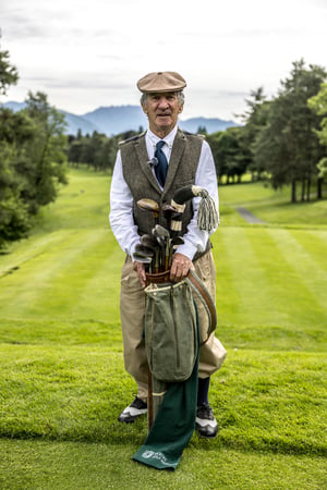 Portrait of a Hickory Masters participant standing with a vintage golf bag and hickory clubs on the fairway.