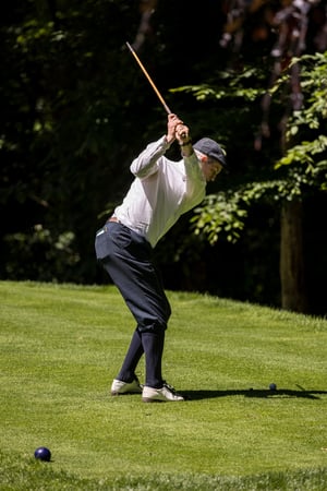Golfer lining up a putt with a vintage hickory putter on the green.