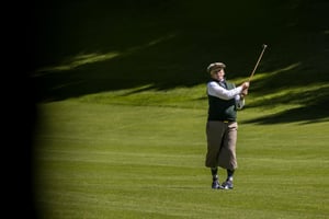 golfer wearing traditional golf clothing finishing a swing with a hickory club on the course at Villa d’Este.