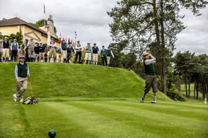 Golfer teeing off with a hickory club while fellow participants watch during the Hickory Masters tournament.