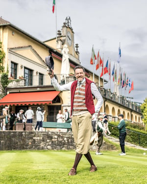 Participant in vintage golf attire greeting spectators in front of the Villa d’Este clubhouse during the Hickory Masters.
