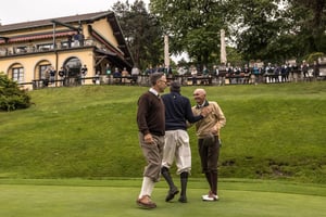 Hickory golfers congratulating each other on the green in front of spectators gathered outside the clubhouse.
