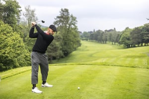 Hickory golfer in vintage-inspired attire preparing to drive from the tee with a wooden club on the Villa d’Este golf course.