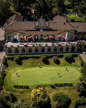 Aerial view of the historic clubhouse overlooking the putting green, with international flags displayed for the Hickory Golf Masters.