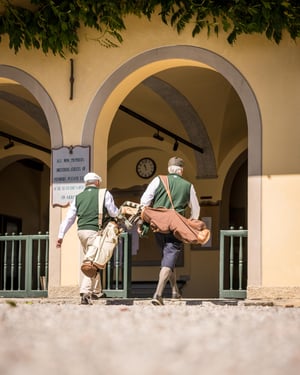 Two hickory golfers carrying vintage golf bags walk into the historic clubhouse before the practice round.