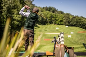 Hickory golfer practicing on the driving range with vintage golf clubs and classic golf bag.