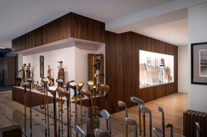 Interior view of the Hickory Golf Masters Museum in Lugano, displaying vintage wooden–shaft golf clubs and historic golf bags in elegant wooden showcases.