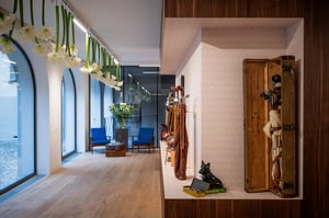 Wide corridor view of the museum featuring hanging white flowers, blue lounge chairs, and vintage golf bags displayed along the wall.