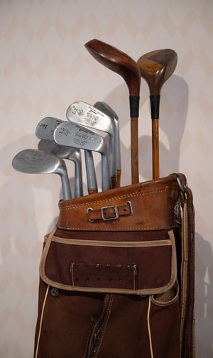 Close-up of a vintage iron clubhead engraved with maker details, highlighting aged patina and hand-forged texture.