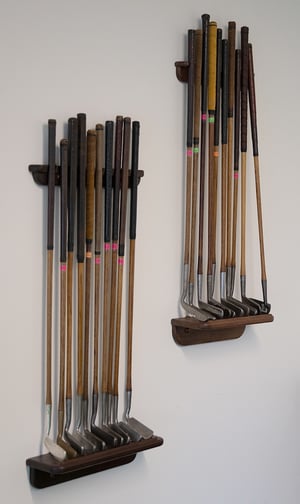 Golden trophy placed atop stacked vintage leather suitcases and several golf books, with a vase of fresh flowers in the background.