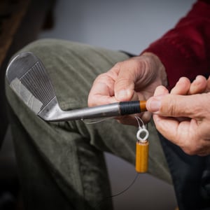 Artisan’s hands wrapping the hosel of a vintage hickory-shaft iron using traditional whipping technique during restoration.