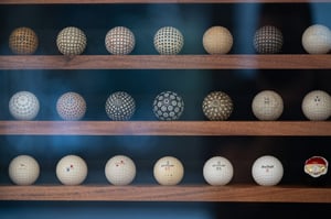 Display shelves showing a curated collection of historical golf balls with various textures and patterns.