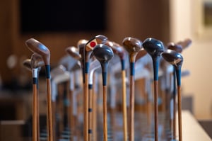 Front-facing view of wooden-head golf clubs arranged in rows, highlighting the craftsmanship and variety of hickory club designs.
